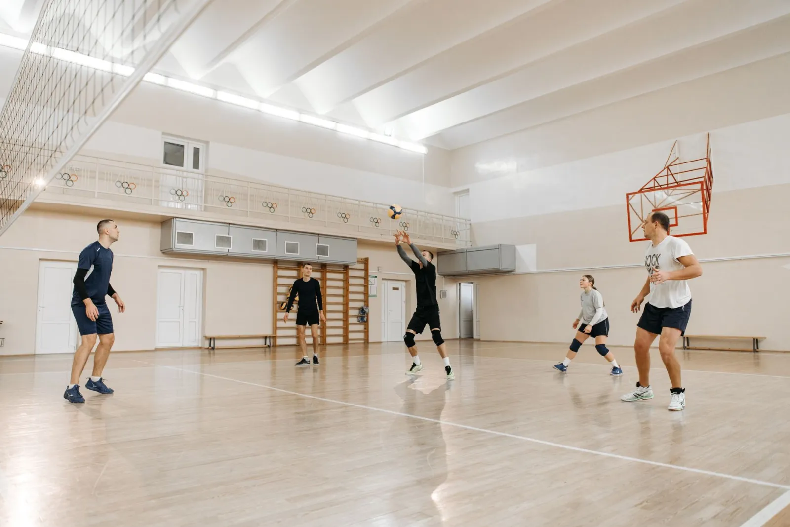 Group of athletes playing volleyball indoors, showcasing teamwork and energy.